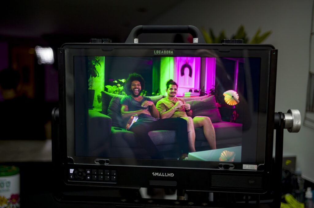 Two male actors are shown on a monitor on a video production set.